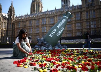 SUKARELAWAN meletakkan bunga pada replika menggambarkan bom Mark-84 seberat 907 kilogram bertulis 'Stop Arming Israel', di perkarangan Dewan Parlimen di tengah London.- AFP