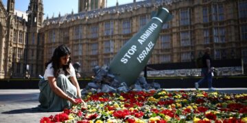 SUKARELAWAN meletakkan bunga pada replika menggambarkan bom Mark-84 seberat 907 kilogram bertulis 'Stop Arming Israel', di perkarangan Dewan Parlimen di tengah London.- AFP