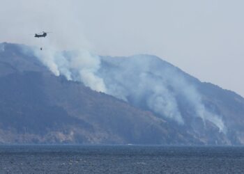 SEBUAH helikopter melalui kawasan dipenuhi kepulan asap ekoran kebakaran hutan di lereng gunung berhampiran bandar Ofunato, wilayah Iwate, kelmarin.- AFP