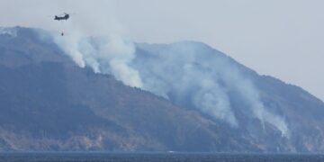 SEBUAH helikopter melalui kawasan dipenuhi kepulan asap ekoran kebakaran hutan di lereng gunung berhampiran bandar Ofunato, wilayah Iwate, kelmarin.- AFP