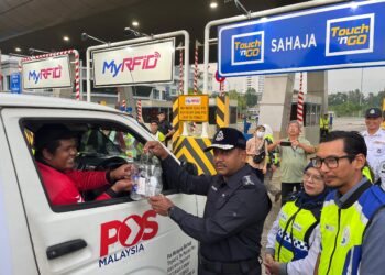 HUSSEIN (tengah) memberi cenderahati kepada pengguna jalan raya di Plaza Tol Kajang Selatan, Lebuhraya Kajang - Seremban (Lekas), di sini, hari ini.