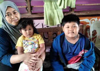 Nor memangku anak bongsunya dan anak lelakinya ketika ditemui di PPS Sekolah Kebangsaan Kampung Maju Jaya