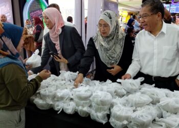 SAPNA Turmidi (kanan) menyampaikan bubur lambuk kepada pengunjung Kompleks PKNS Shah Alam, Selangor semalam-UTUSAN/ MOHAMAD NAUFAL MOHAMAD IDRIS