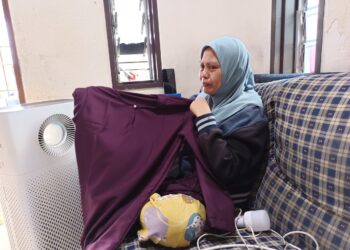 NOR Hafizah Mohd. Sheriff sebak ketika menunjukkan baju Melayu yang dibeli buat arwah suaminya yang meninggal dunia dalam kemalangan jalan raya, kelmarin. - UTUSAN/NOR AINNA HAMZAH