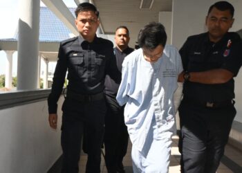 TERTUDUH diiringi anggota polis ketika dihadapkan ke Mahkamah Majistret, Ayer Keroh, Melaka atas pertuduhan membunuh. - UTUSAN/MUHAMMAD SHAHIZAM TAZALI