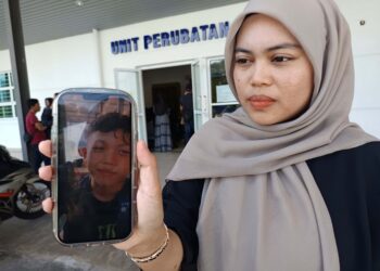 ROSALIAH Diego, 26, menunjukkan gambar Muhammad Aidil Ramdan Abdullah, 15, ketika ditemui di pekarangan Unit Perubatan Forensik Hospital Rembau, hari ini.-UTUSAN/NOR AINNA HAMZAH.