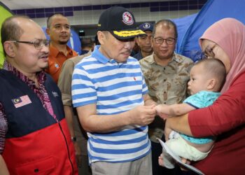 HAJIJI Noor (dua kiri) bersama Shamsul Iskandar Mohd Akin (kiri) menyantuni mangsa banjir yang ditempatkan di PPS Dewan Datuk Seri Panglima Mohd Dun Banir, Beaufort, Sabah hari ini