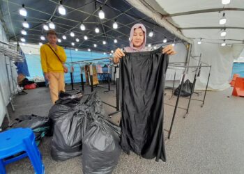 DYA MELI Asman menunjukkan baju raya yang dijual basah apabila gerainya di Bazar Raya Kota Tinggi dilanda banjir semalam.