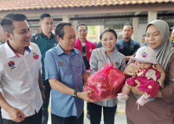 AHMAD MASLAN (dua dari kiri) menyampaikan bantuan kepada mangsa banjir yang ditempatkan di Pusat Pemindahan Sementara (PPS) SMK Seri Perdana di Kluang hari ini.