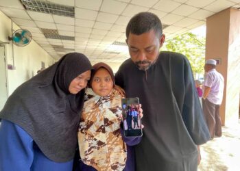 MOHD. Niza Nazari (kanan) dan isteri, Norhayati Ariffin (kiri) serta anak mereka, Nur Qaisara menunjukkan gambar Muhammad Danish Iqbal bersama Muhammad Dhani Arumi Mohd. Azlan ketika ditemui  di pekarangan Jabatan Forensik HSB di Alor Setar, Kedah, semalam.