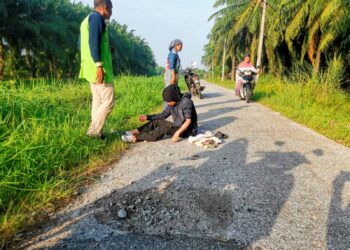 KEADAAN penunggang motosikal yang terjatuh akibat terlanggar lubang di satu laluan dikenali ‘laluan belakang’ di Kampung Bahagia di Teluk Intan. – UTUSAN/AIN SAFRE BIDIN.