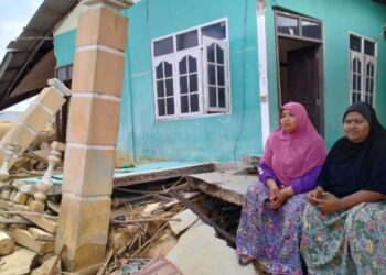 NORAINI Nawi (kiri) bersama kakaknya hanya mampu termenung memikirkan masa depan selepas rumah mereka runtuh dihanyutkan arus deras semasa banjir di Kampung Jubakar Pantai, Tumpa, Kelantan. - UTUSAN/ROHANA ISMAIL