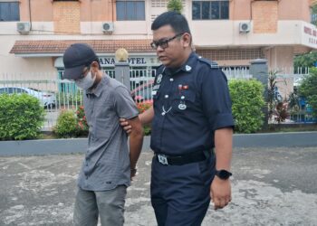 ANGGOTA polis mengiringi Wan Muhammad Faezyl Wan Mansor keluar dari Mahkamah Majistret Kemaman, Terengganu. -UTUSAN/NIK NUR IZZATUL HAZWANI NIK ADNAN