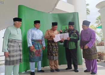 AMINUDDIN Harun melihat buku projek Bandar Wakaf Malaysia-Gaza yang disampaikan oleh Sani Araby pada Majlis Pelancaran Tabung Apartmen Wakaf Negeri Sembilan di Masjid Negeri, Seremban, semalam.-UTUSAN/NOR AINNA HAMZAH.