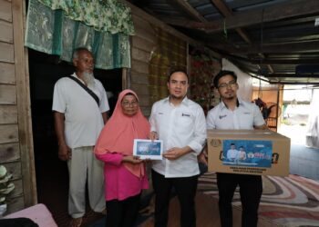 AHMAD Farhan memberi sumbangan kepada isteri nelayan, Saluna Mat Jusoh di Kampung Cherating, Kuantan sempena program Ziarah Madani, hari ini.