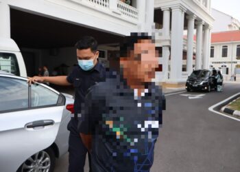 SEORANG pekerja penyelenggaraan diiringi oleh anggota polis ketika dibawa ke Mahkamah Majistret George Town, Pulau Pinang untuk mendapatkan perintah reman berhubung kes penemuan sebuah beg berisi peluru di tempat pembuangan sampah di Bukit Jambul, Pulau Pinang, kelmarin. -UTUSAN/IQBAL HAMDAN