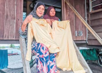 ZAINAP Ishak menunjukkan baju Melayu Teluk Belanga kesukaan anaknya, Yahya Harun yang hilang sejak lapan bulan lalu ketika ditemui di Kampung Panchor, Pantai Remis. - UTUSAN/AIN SAFRE BIDIN