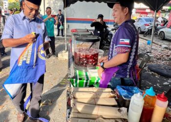 AFFENDI Rajini Kanth (kiri) menyerahkan apron kepada salah seorang peniaga semasa melakukan tinjauan di bazar Ramadan Kangar, Perlis, semalam.- UTUSAN/ASYRAF MUHAMMAD