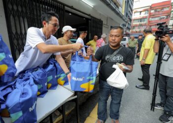 MOHD Iqmal Muslim (kiri) mengedarkan makanan kepada gelandangan pada Program Pengagihan Makanan kepada Gelandangan di Pusat Pembelajaran Komuniti Chow Kit. UTUSAN/FARIZ RUSADIO