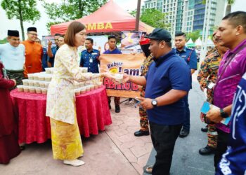 SANDREA Ng Shy Ching menyampaikan bungkusan bubur lambuk kepada pengunjung Bazar Ramadan Bulatan Sultan Azlan Shah di Ipoh Perak, semalam. - UTUSAN