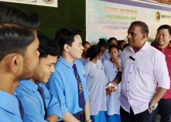 M. SARAVANAN berbual dengan pelajar pada program sumbangan duit raya  di Tapah hari ini.- UTUSAN