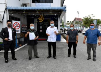 MUHYIDDIN Abdul Rashid (tengah) menunjukkan laporan polis terhadap sebuah portal berita di Ibu Pejabat Polis Daerah (IPD) Kuala Terengganu di Kuala Terengganu pada 8 Jun 2021