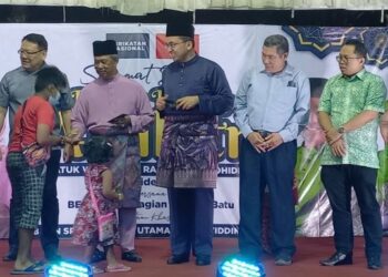 MUHYIDDIN Yassin (dua, kiri) menyampaikan duit raya kepada kanak-kanak yang menghadiri Rumah Terbuka Aidilfitri Bersatu Bahagian Tangga Batu di Dewan Kompleks Sukan Komuniti Krubong, Melaka. - UTUSAN/AMRAN MULUP