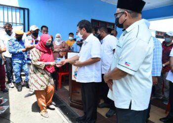 MOHD. Shafie Apdal (dua kanan) menyampaikan bantuan kepada salah seorang mangsa kebakaran di Semporna hari ini.