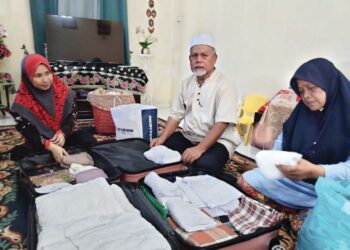 SARKAWI Banjar (tengah), Siti Rodiah Mardi (kanan) dan Shahaniza mengemas barangan kelengkapan bagi menunaikan haji di rumah mereka di Kampung Parit Marjunid, Benut, Pontian, Johor.