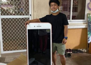 REMAJA dari Thailand berdiri bersama meja kopi berbentuk seperti iPhone yang diterimanya. - AGENSI