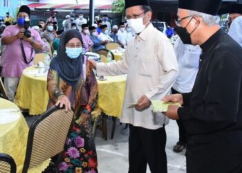 MOHD. Shafie Apdal (tengah) menyampaikan sumbangan kepada salah seorang penerima di Kampung Benoni, Papar semalam.