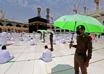 ANGGOTA keselamatan Arab Saudi memegang payung semasa umat Islam menunaikan ibadah Umrah di Masjidil Haram di Mekah. - AFP