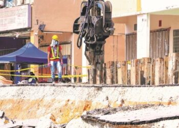 KONTRAKTOR giat melakukan kerja-kerja pemasangan cerucuk bagi menahan pergerakan tanah dalam kejadian tanah mendap dan runtuhan berhampiran longkang di deretan kedai Jalan LP 1A/2 Lestari Perdana. - UTUSAN/FARIZ RUSADIO