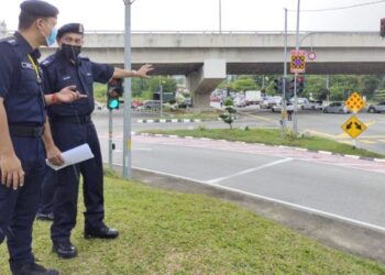 SHAFIEI Muhamad (kanan) memantau pergerakan aliran trafik di persimpangan lampu isyarat di Seremban Gateway, Seremban hari ini.