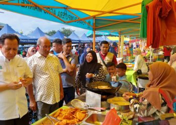 ABDUL HALIM Hussain (kiri) mencuba keenakan cucur dan kuih tempatan sempena program jualan PAM di pekarangan Masjid As-Solihin, Kampung Kepala Gajah di Simpang Ampat, Pulau Pinang baru-baru ini.