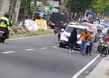 TANGKAP layar video menunjukkan seorang wanita berjalan di tengah jalan raya di Magetan, Jawa Timur, Indonesia. - AGENSI