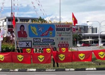 LINA Soo bergambar di hadapan sepanduknya yang memaparkan simbolik ‘Bebaskan Sarawak dari Malaysia’ berupa sebilah gunting di tengah Laut China Selatan sebelum diturunkan oleh Parti Aspirasi selepas diarahkan oleh Suruhanjaya Pilihan Raya (SPR).