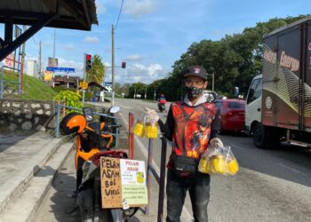 Muhammad Nasib Zakir menjual jeruk mangga asam boi di persimpangan lampu isyarat berhampiran Econsave Taman Daiman di Kota Tinggi.