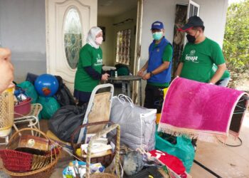 RAVI Muthayah  (bertopi biru) dan Daroyah Alwi membantu mengemas dan membersihkan kediaman mangsa banjir di Kampung Asahan, Kuala Selangor, hari ini.