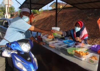 Zanariah melayan pelanggan membeli sarapan di gerainya di Felda Gugusan Jelai, Tampin.-UTUSAN/NOR AINNA HAMZAH.