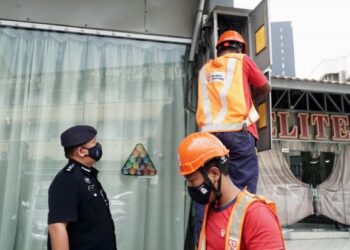 ASMADI Abdul Aziz (kiri) melihat pekerja TNB memotong bekalan elektrik di premis perjudian haram di Ipoh hari ini. - FOTO/ZULFACHRI ZULKIFLI