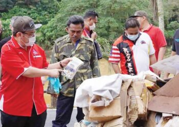 ABDUL Fattah Abdullah (dua dari kiri) melibat buku sekolah yang rosak ekoran kejadian banjir di SMK Orang Kaya Haji di Lipis, Pahang semalam.