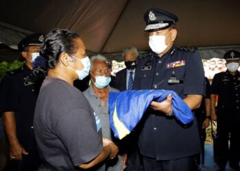 ABDUL Hamid Bador (kanan) menyerahkan Jalur Gemilang kepada balu Koperal Baharuddin, Relow Ko, 48, sambil diperhartikan oleh bapa mendiang, Ramli Derus, 75 ketika hadir memberikan penghormatan terakhir pada majlis pengkebumian di Tanah Perkuburan Orang Asli, Kampung Sungai Sampo, Air Hitam, Bandar Seri Jempol, Jempol, Negeri Sembilan hari ini. - FOTO/NOR AINNA HAMZAH