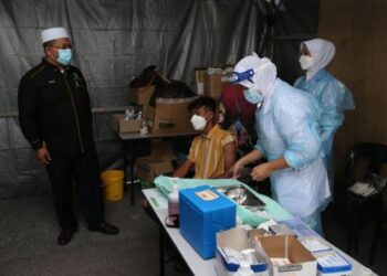 AHMAD Marzuk Shaary (kiri) berbual dengan seorang penerima vaksin di Outreach Vaksinasi Covid-19 di Masjid As-Salam di Pengkalan Chepa, Kota Bharu, hari ini. - FOTO/ROHANA MOHD. NAWI