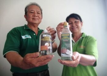 JALIMAH (kanan) bersama suaminya menunjukkan produk minyak kelapa dara di Kudat baru-baru ini.