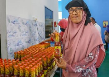 NORLI Hamzah menunjukkan salah satu produk sos ikan bakar yang dihasilkan oleh syarikatnya di Sungai Petani baru-baru ini.