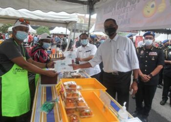 ALEXANDER Nanta Linggi (belakang, tengah) memberi kit cecair pembasmi kuman kepada peniaga ketika meninjau Bazar Ramadan Presint 3 di Putrajaya hari ini. -FOTO/FAISOL MUSTAFA