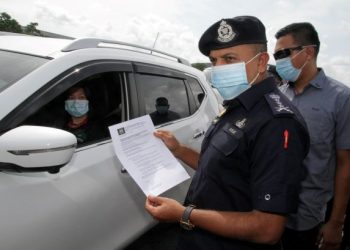 AYOB Khan Mydin Pitchay (kanan) memeriksa surat pelepasan rentas sempadan di Plaza Tol Skudai, Johor Bahru hari ini. - FOTO/BAAZLAN IBRAHIM 