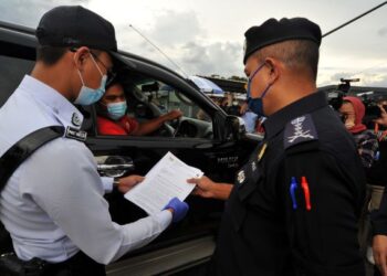 AYOB Khan Mydin Pitchay (kanan) meneliti dokumen perjalanan seorang pemandu kenderaan ketika meninjau SJR di Seelong, Johor Bahru. - FOTO/RAJA JAAFAR ALI