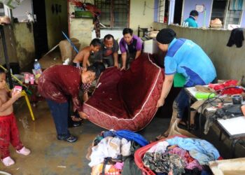 Sebuah keluarga dari Kampung Sepakat Batu, Skudai, Johor Bahru membersihkan rumah mereka yang terjejas akibat banjir, semalam. – UTUSAN/RAJA JAAFAR ALI.